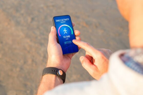 Man using daily activity tracking app on mobile phone showing 10,000 steps daily goal achievement