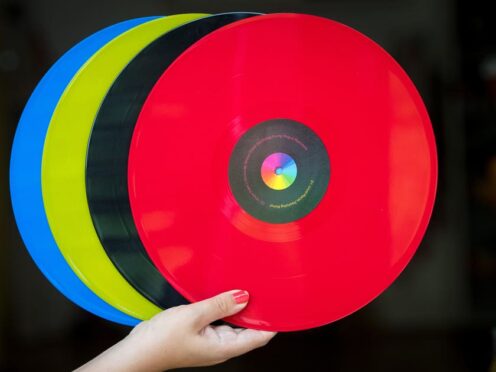A woman holds 12 inch vinyl records (Dominic Lipinski/PA)