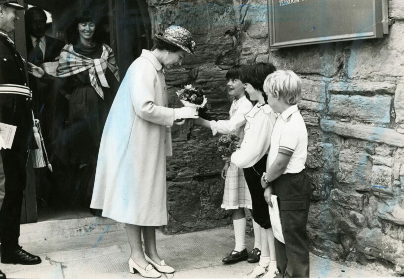 The Queen receives posies of flowers from children at Anstruther Museum. 