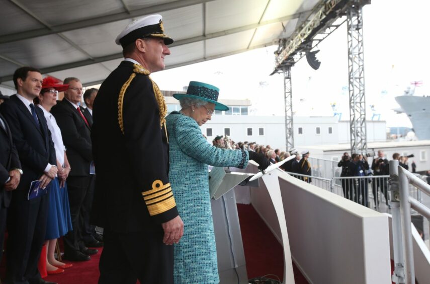 Queen Elizabeth II pressing the button to release the bottle of whisky at Rosyth Dockyard, Fife to formally name the Royal Navy's biggest ever ship, HMS Queen Elizabeth. 