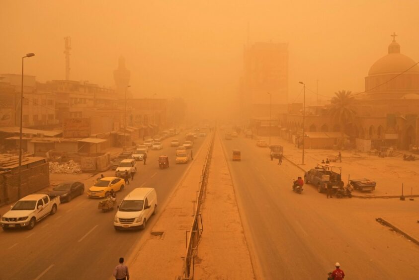 People navigate a street during a sandstorm in Baghdad, Iraq. AP Photo/Hadi Mizban.