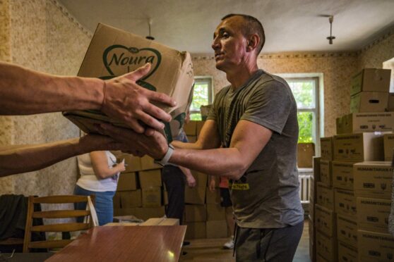 A volunteer unloads boxes of humanitarian aid in Kostiantynivka. Access to some goods and food in Donbass is very complicated because of the fighting between Russia and Ukraine. Celestino Arce Lavin/ZUMA Press Wire/Shutterstock.