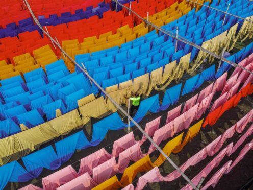 Workers hang thousands of metres of different coloured fabrics to dry