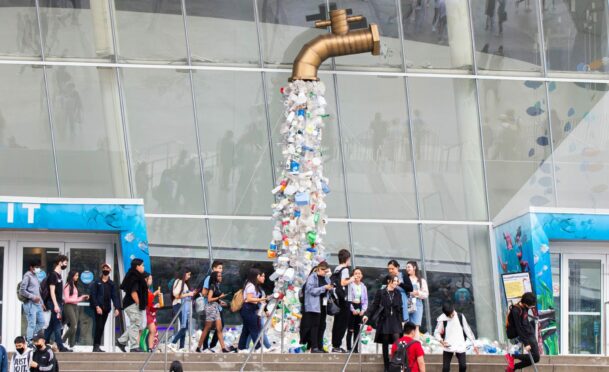 People walk past the art installation "Turn Off The Plastic Tap" outside the Ripley's Aquarium of Canada in Toronto