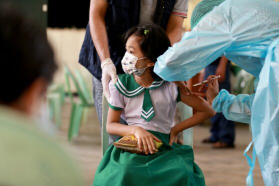 A student receives a dose of COVID-19 vaccine at a school in Yangon