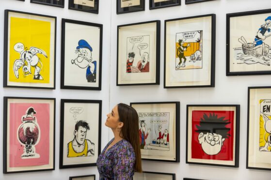 A staff member views "a selection of comic art screenprints including Beano and Asterix",  from the 2010s and 2020s.