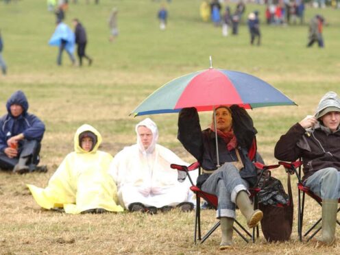 Spectators braving the rain during the 2004 Glastonbury festival (Yui Mok/PA)