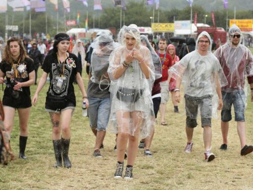 Festival goers during a rain shower at the Glastonbury Festival (PA)