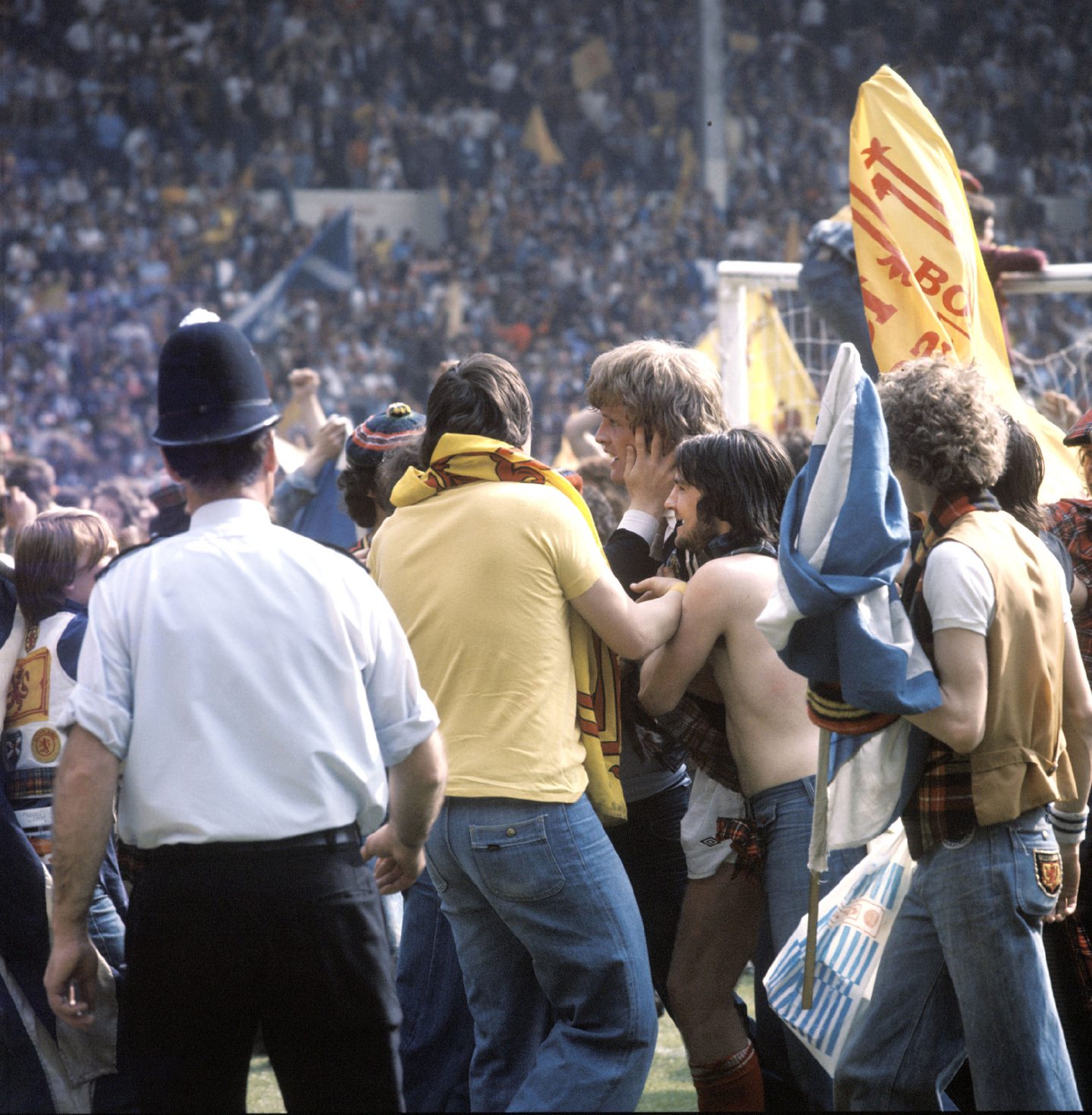 Scotland fans celebrate with Gordon McQueen, centre, on the pitch after their victory