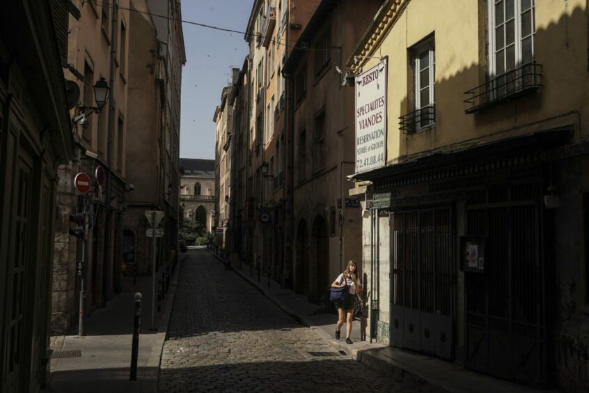 A woman walks in the street during a heat wave in Lyon, central France.