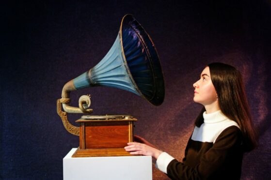 A gallery assistant looks at a vintage horn gramophone belonging to John Peel