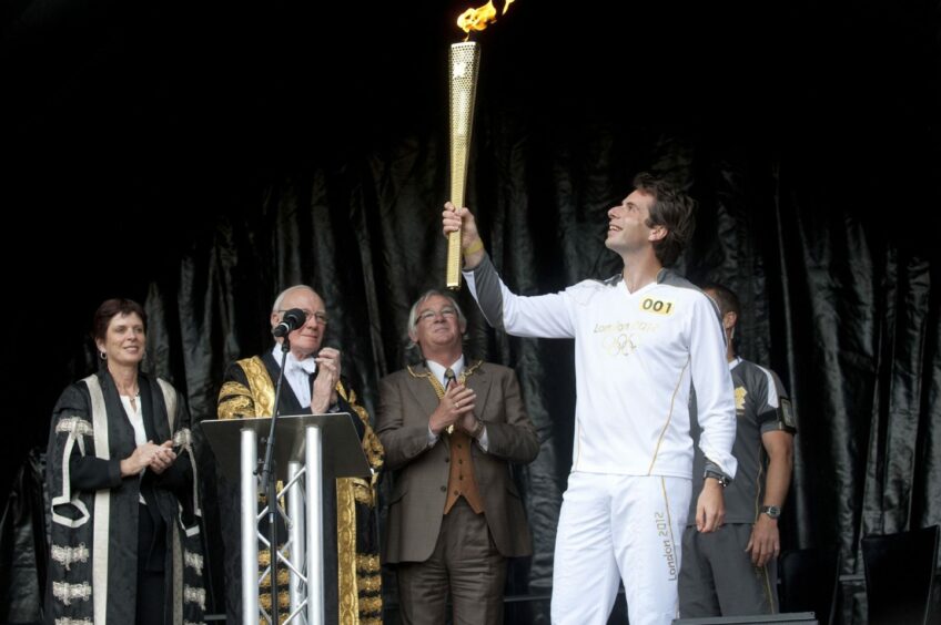 Round the world cyclist Mark Beaumont holding the torch in St Andrews.