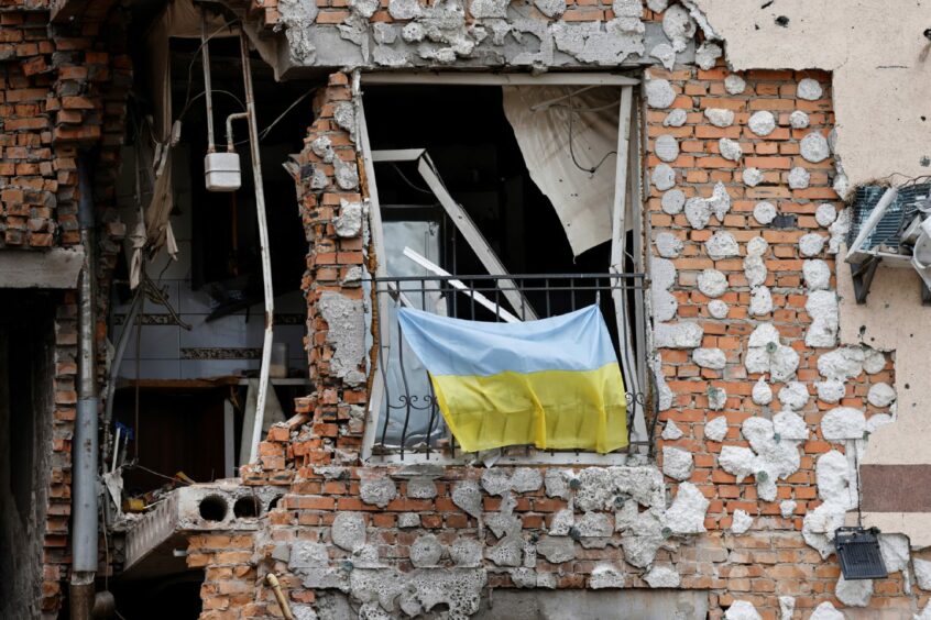 A Ukrainian national flag hangs from a balcony of a civilian destroyed building in Irpin, outside Kyiv