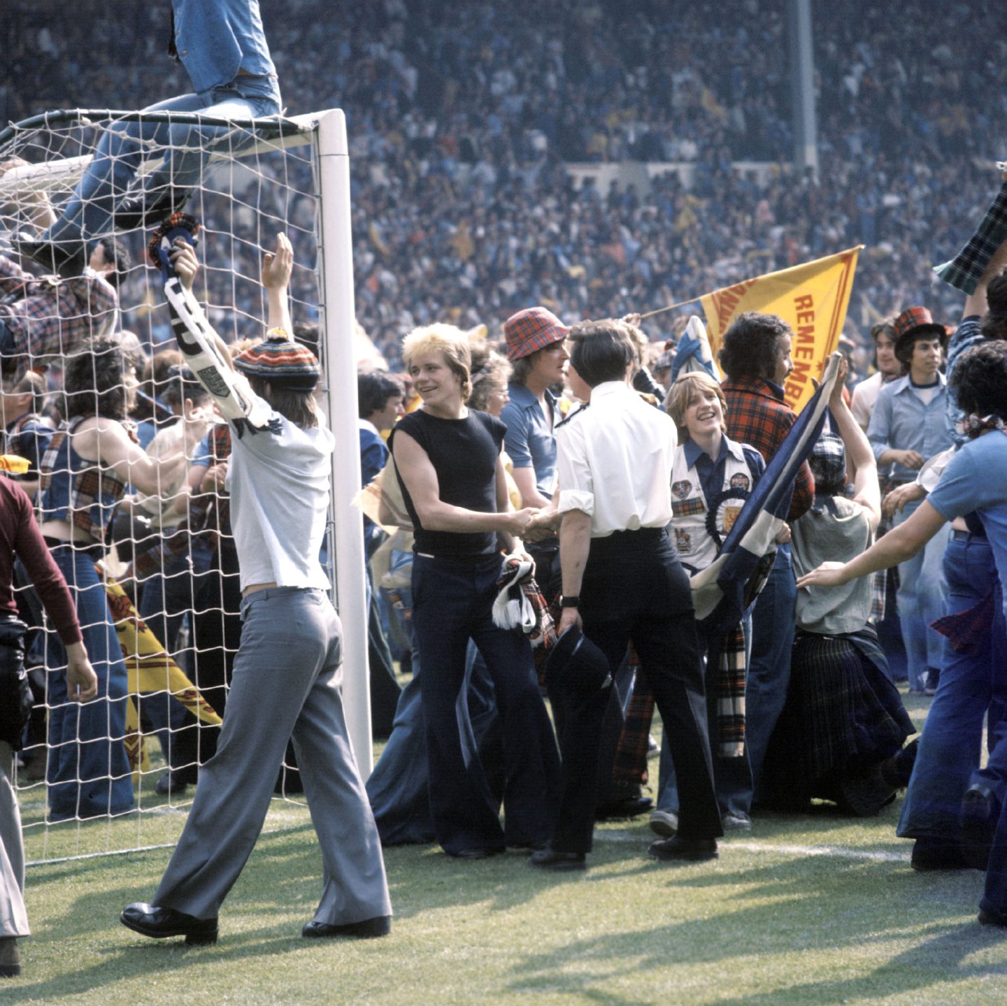 Scotland fans celebrate on the pitch after their team's victory.