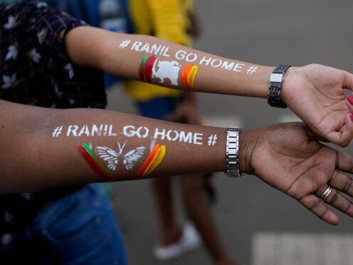 Girls display their arms painted with message ‘Ranil go home’, referring to Ranil Wickremesinghe, at a protest in Colombo (AP)