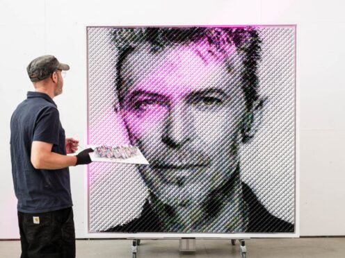 Artist Joe Black adds the finishing touches to a portrait of David Bowie (John Nguyen/PA)