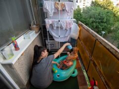 Krisztina plays with her children on their balcony in Budapest, Hungary (Anna Szilagyi/AP)