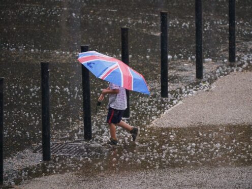 A young boy with an umbrella walking through puddles on Bankside in London (Yui Mok/PA)