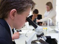 Secondary school students using microscopes during a GCSE science class (Alamy/PA)