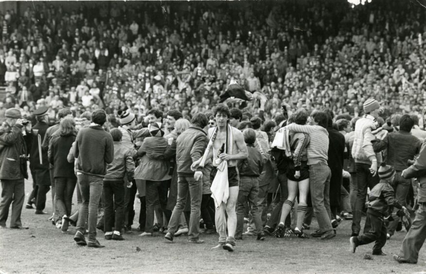 Holt celebrates with the fans as United's David Narey emerges through the crowd without his shirt at Dens in 1983.