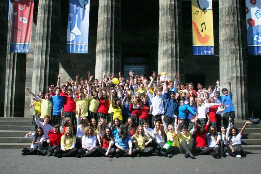 Pupils gathered and waving for the camera in front of the High School of Dundee's pillars.