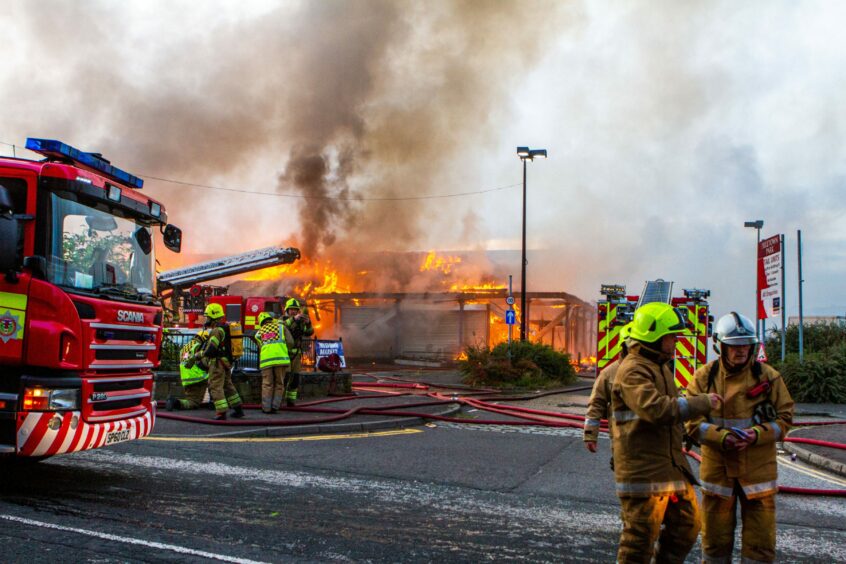 Emergency crews at the scene on September 12 2018, with the building on fire in the background.