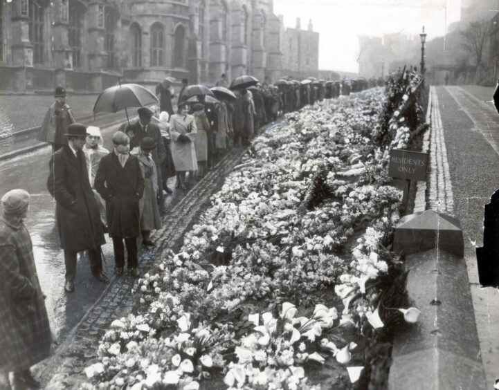 People stopping to view the funeral wreaths which had been placed outside the Palace