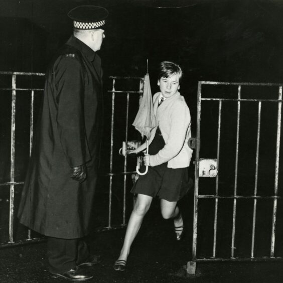 A girl pupil leaves through the school gate after the needlework class was held up at gun point. Image: DC Thomson.