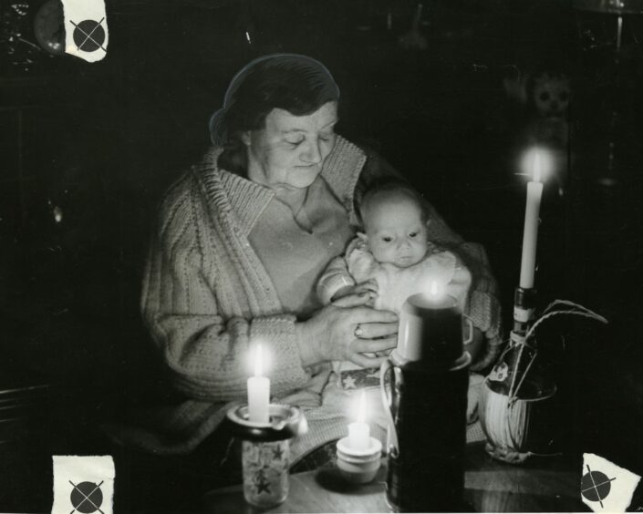 Mrs Robena Armour nurses her grandson Mark by candlelight in February 1972.