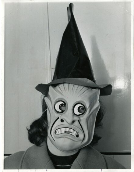 Image shows a Halloween guiser in a spooky mask and witches hat for the occasion