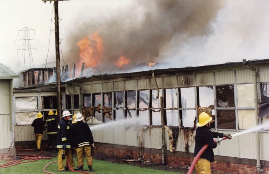 The charred remains of the school building can be seen as firefighters attempt to tackle the blaze. 