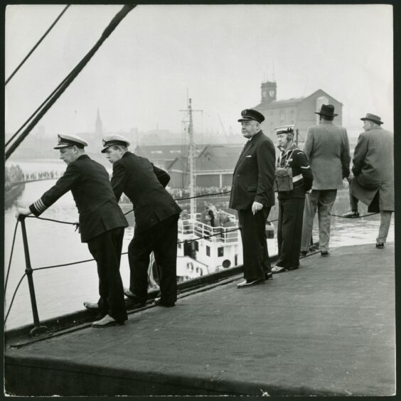 Left to right: Capt. Peter Sime, Lt. Com. Hall, and Tay Pilot Dew watch from the deckhouse as Unicorn is moved from one berth to another.