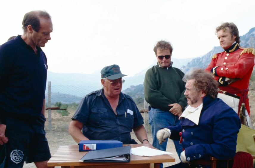 Brian Cox talking to production crew during a break from filming. 