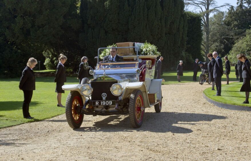 Staff of Beaulieu line the route of Lord Montagu's coffin, carried on his beloved 1909 Rolls-Royce Silver Ghost, as it leaves his home Palace House on September 10 2015.