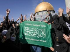 Palestinians holding a Hamas flag, protest by the Dome of the Rock Mosque at the Al-Aqsa Mosque compound in the Old City of Jerusalem, Friday, Jan. 27, 2023. The protest was a day after the deadliest Israeli raid in decades and raised the prospect of a major flare-up in fighting. (AP Photo/Mahmoud Illean)