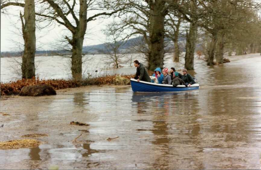 The Lang family from Little Fardle, by Meklour, approaching dry land after their house was flooded when the Tay burst its banks. Image: DC Thomson.