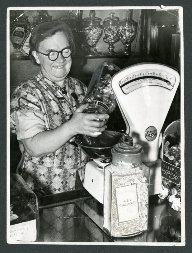 An assistant measures out a weight of sweets from a jar in a Hilltown Shop in 1954 after all rationing ended. Image: DC Thomson.