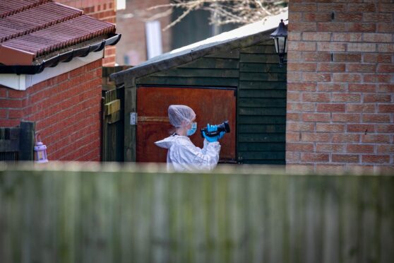 Forensic officers taking photographs of the interior and exterior of the scene in Troon Avenue, Dundee. 