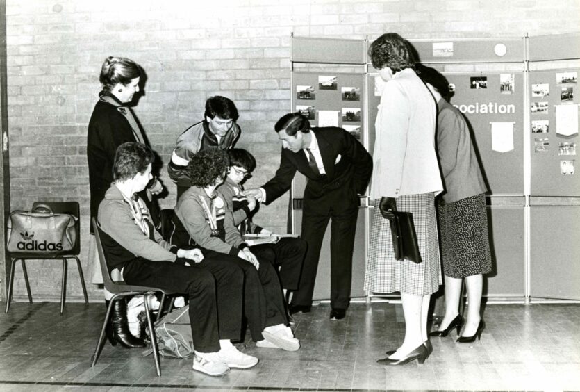 Charles examines the medals won by disabled Fife swimmer Douglas Lord. Image: DC Thomson.