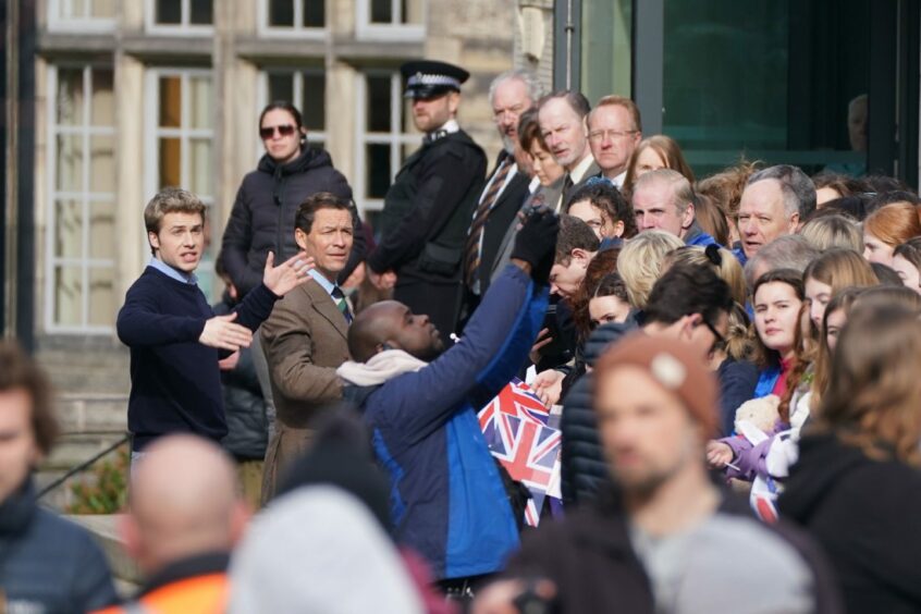 Ed McVey, playing the part of Prince William, and Dominic West, playing the part of the Prince of Wales, meeting crowds in St Andrews as part of a scene for season six of The Crown.