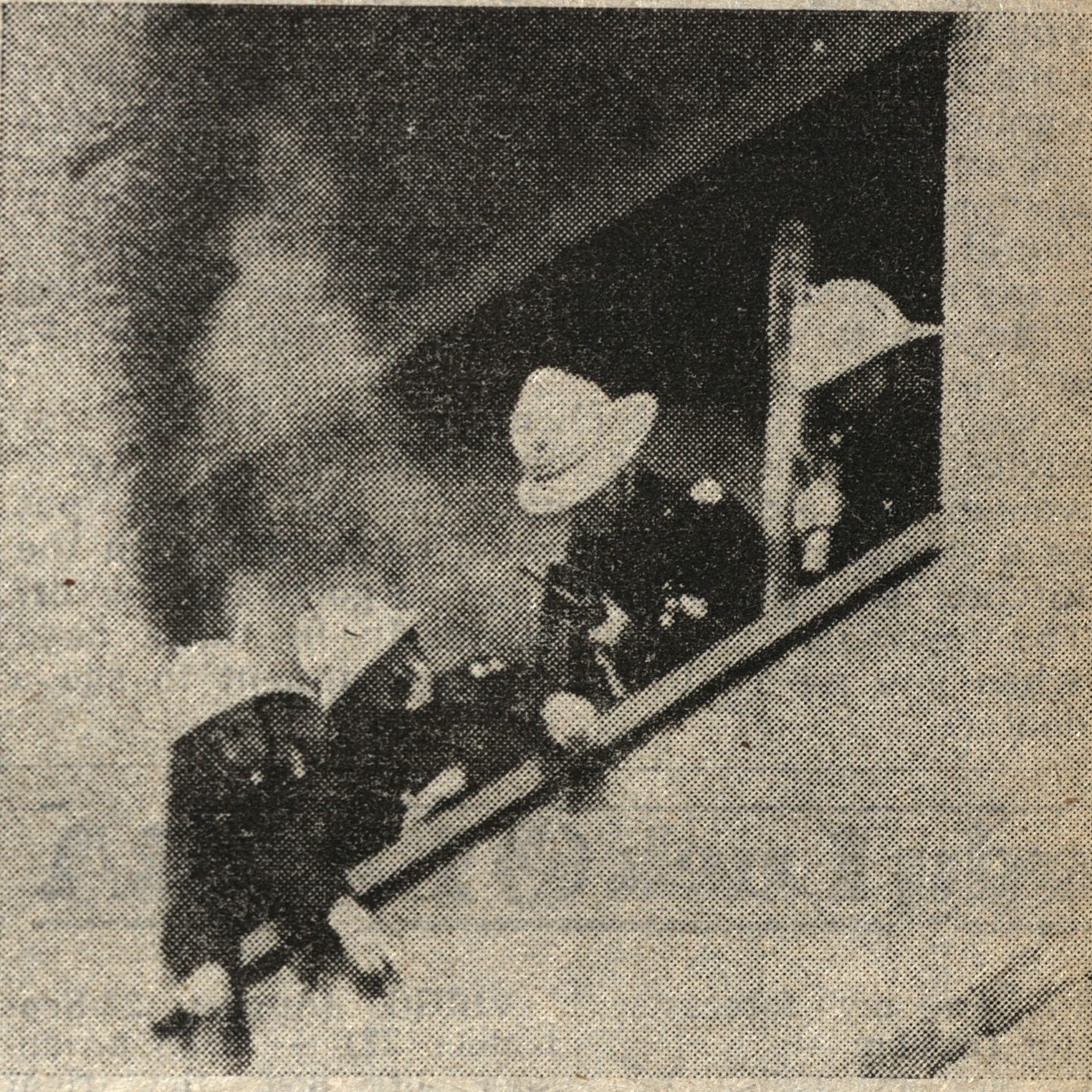 Firefighters standing at the window as smoke billows behind them from a flat. Image: DC Thomson.