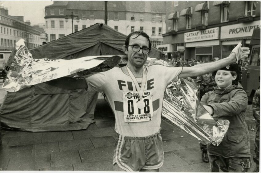 Don MacGregor stretches out his arms in celebration after finishing the marathon