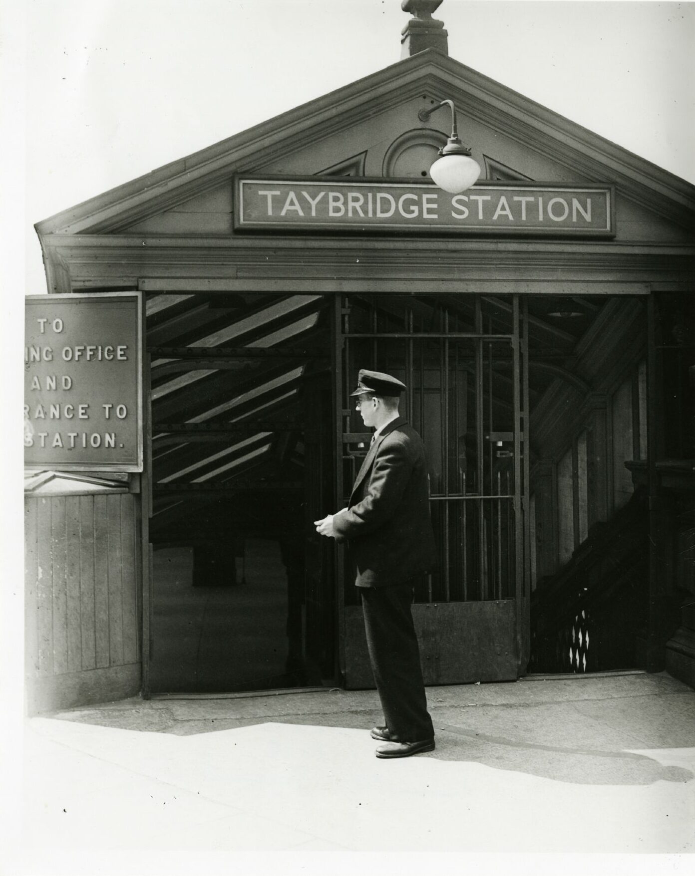 A train conductor standing by the entrance of Tay Bridge Station in Dundee.
