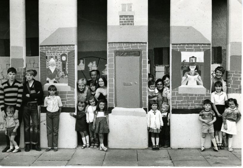 Committee members, helpers and children posing beside the multi murals they made in 1981. Image: DC Thomson.