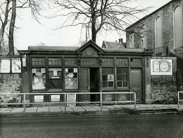 Jim Brady's shop in Lochee Road with several posters in the window. Image: DC Thomson.