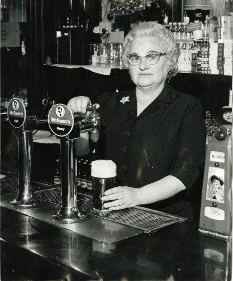 Mrs Isobel Mennie pouring a final pint before retiring in 1972. Image: DC Thomson.