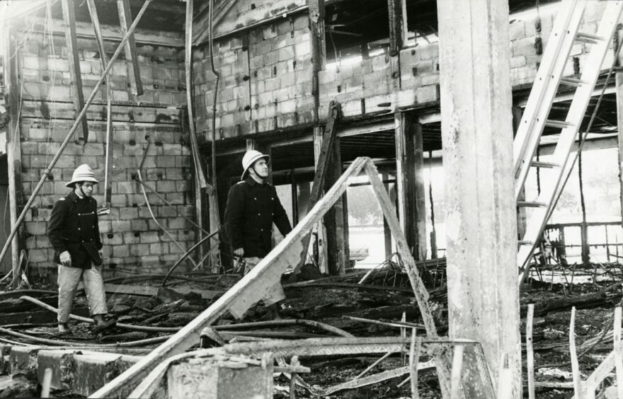 Two firemen walking through the rubble and skeleton of the building. Image: DC Thomson.