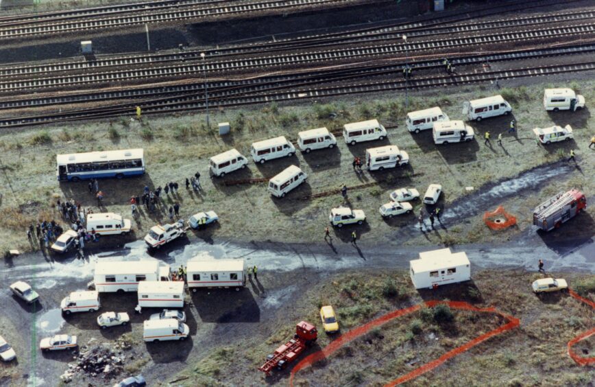An aerial image shows several vans and a small crowd standing next to the railway line. Image: DC Thomson.