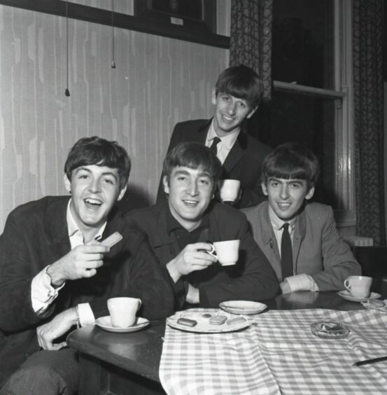 The Beatles enjoying tea and biscuits backstage at the Caird Hall. Image: DC Thomson.