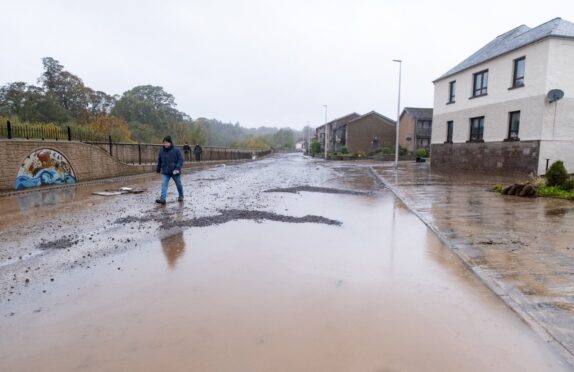 A man walks down a flooded street, as some homes in Brechin remain cut off. Image: Paul Reid.